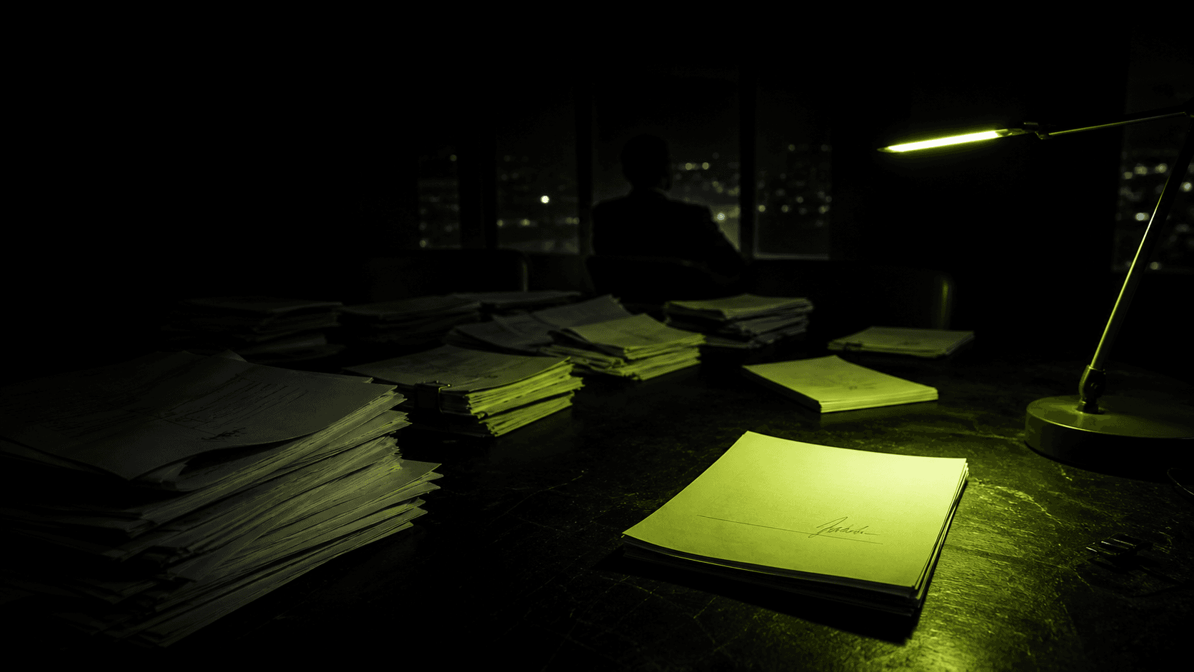 A signed term sheet lit by a single electric-lime desk lamp in a dark investment office